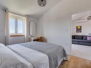 ein weißes Schlafzimmer mit einem Bett und einer Couch in der Unterkunft Apartment Bonex-2 by Interhome in Privlaka