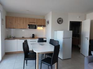 a kitchen with a table and chairs and a white refrigerator at Apartment SC C06 by Interhome in Mimizan