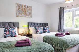 zwei Betten in einem Schlafzimmer mit lila Handtüchern darauf in der Unterkunft Stylish 3 bedroom House In Grt Gregorie Basildon & Essex - Free Wifi, Parking, Dedicated Office & Private Garden in Basildon