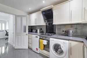eine Küche mit weißen Schränken und einer Waschmaschine und einem Trockner in der Unterkunft Stylish 3 bedroom House In Grt Gregorie Basildon & Essex - Free Wifi, Parking, Dedicated Office & Private Garden in Basildon