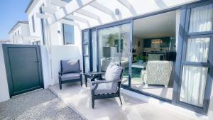 a patio with two chairs and a table and windows at 10 Seaview Close, Shelley Point in St Helena Bay