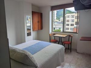 ein Schlafzimmer mit einem Bett, einem Tisch und einem Fenster in der Unterkunft Hotel Armont Calarca in Calarcá