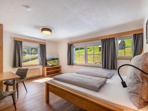 a bedroom with a bed and a desk and windows at Apartment Grimming by Interhome in Kleinsölk