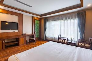 a hotel room with a bed and a flat screen tv at River Bank Jungle Resort, Chitwan in Bharatpur