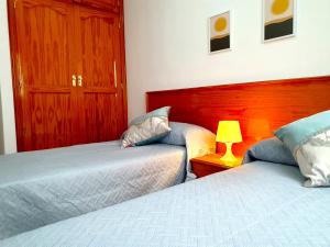 ロス・アブリゴスにあるSeaside Whale Apartments WIFI 1Dのベッドが2つとテーブルの上にランプが置かれた寝室