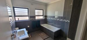 ケープタウンにあるFamily holiday home to rentのバスタブと洗面台のあるバスルーム +8枚の写真