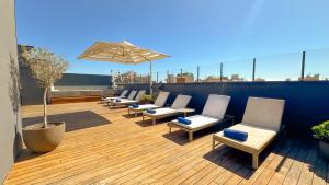 a row of chairs and an umbrella on a rooftop at Room Mate Collection Gerard, Barcelona in Barcelona