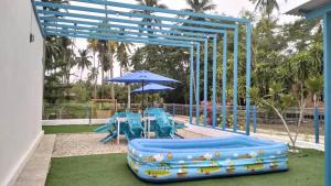 a playground with blue tables and an umbrella at Villa Beradu Cherating ,Three bedroom house in Cherating