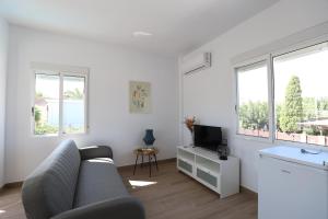un soggiorno bianco con un divano e una TV di 2 apartamentos en una excelente villa de playa compartiendo Piscina y Jardín a Sagunto
