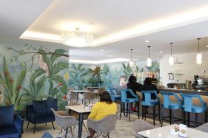 people sitting at tables in a restaurant with a mural of plants at Yaya Hotel & Apartments in Nairobi