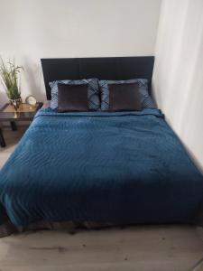 a bed with a blue comforter and two pillows at Apartament Lux2 Konin NOCLEGI in Konin