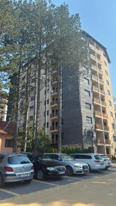 a parking lot with cars parked in front of a tall building at Apartman Divine Lux Zlatibor in Zlatibor