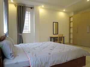 a bedroom with a large bed with a desk and a window at ST Apartment in Phnom Penh