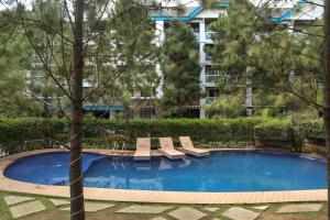 une piscine avec des chaises longues devant un immeuble dans l'établissement Serene Suites Staycation at Pine Suites Tagaytay, à Tagaytay