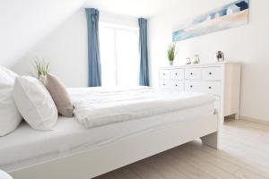 a white bedroom with a bed and a dresser at Ferienhaus Ostseetraum Langholz in Waabs