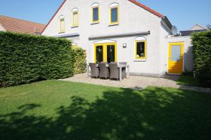 a house with two chairs and a table in the yard at Kustverhuur, Vakantiepark Fort Soleil 24 in Breskens