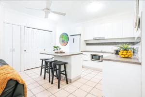 a kitchen with white cabinets and black stools at 12 Central Plaza Port Douglas in Port Douglas