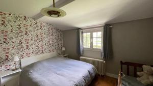 una camera da letto con un letto bianco e una finestra di Les Bruyeres, maison proche mer a Hautot-sur-Mer