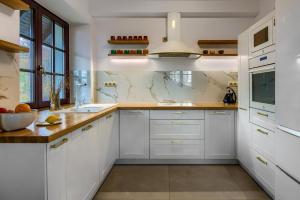 a white kitchen with white cabinets and a sink at Dzikie Historie Młynik in Sorkwity