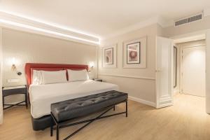 a bedroom with a large bed with a bench in it at Eurostars San Antón in Granada