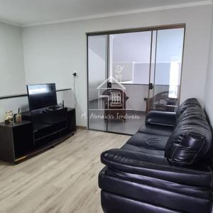 Una sala de estar con un sofá de cuero y un televisor. en Sobrado I Guaiapó, en Maringá