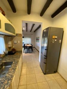 Una cocina con refrigerador de acero inoxidable y una mesa. en SOHO Chacras de Coria Casa Completa, en Chacras de Coria