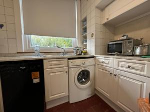 a kitchen with a washing machine and a microwave at 303 Upminster Road North in Rainham +25 photos