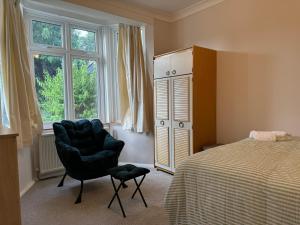 a bedroom with a bed and a chair and a dresser at 303 Upminster Road North in Rainham