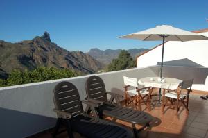 eine Terrasse mit einem Tisch, Stühlen und einem Sonnenschirm in der Unterkunft VV El Almendro in Tejeda