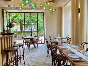 a restaurant with wooden tables and chairs and a large window at Hôtel Restaurant Auprès d'Angèle in Marcillac-Vallon