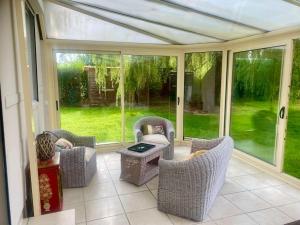 a screened in porch with wicker chairs and a table at Le gîte du marais in Suzanne
