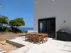 a wooden table and chairs on a patio with the ocean at mahaloha house 新築ビーチフロント ペット同伴プラン有 ｍax8名 BBQ 海歩1分 アイランドキッチン 大型プロジェクタ 床暖房 オーシャンビューバス in Isumi
