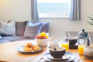 Una mesa con un bol de fruta y un plato de comida. en Apartment 17, The Moorings - Stunning sea views, en Filey