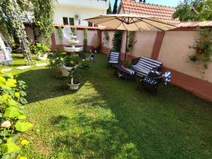 a backyard with two benches and an umbrella at Apollon home apartments in Bar