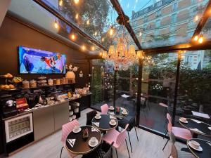 a dining room with tables and chairs and a tv at Glam's Hotel in Paris