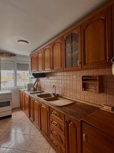 a kitchen with wooden cabinets and a sink at Grand House Apartment in Selitë e Vogël