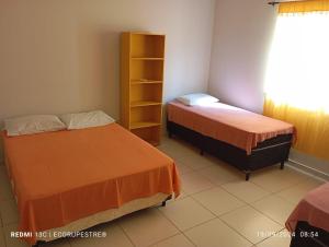 a room with two beds and a book shelf at EcoRupestre Hostel & Receptivo in São Raimundo Nonato