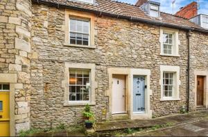 a stone house with a blue door and windows at Rose & Star Cottage in Frome