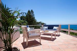un patio con mesa, sillas y el océano en Seabreeze Luxury Two Bedroom Self Catering Penthouse en Simonʼs Town