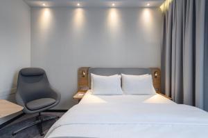 a hotel room with a bed and a chair at Holiday Inn Express Munich Airport - Erding by IHG in Erding +2 photos