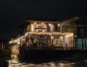 a house with lights on the water at night at เฉื่อยโฮมสเตย์ in Nonthaburi