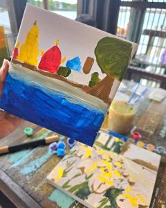 a person holding up a painting of a painting of a painting at เฉื่อยโฮมสเตย์ in Nonthaburi