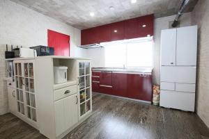 a kitchen with red cabinets and a white refrigerator at TR Niseko House Room New York in Niseko