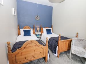 two twin beds in a room with blue walls at East Crossthwaite Cottage in Newbiggin