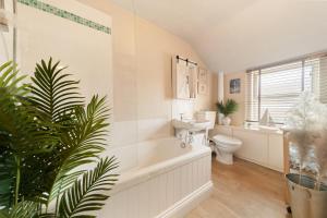 a bathroom with a tub and a toilet and a sink at Cottage On The Common in Great Malvern