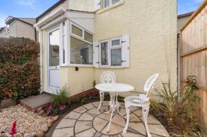 a patio with a table and chairs in front of a house at Cottage On The Common in Great Malvern