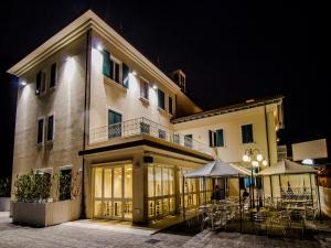 a building with tables and chairs in front of it at night at Hotel Butterfly in Torre del Lago Puccini