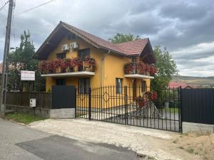 a yellow house with flower boxes on a fence at Casa Luna in Floreşti