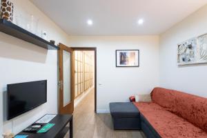 een woonkamer met een rode bank en een flatscreen-tv bij Bonito piso cerca de park guell in Barcelona