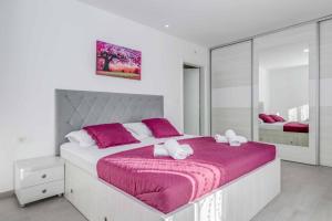 een witte slaapkamer met een groot bed met paarse lakens bij Villa Great Escape in Šumet +45 foto's